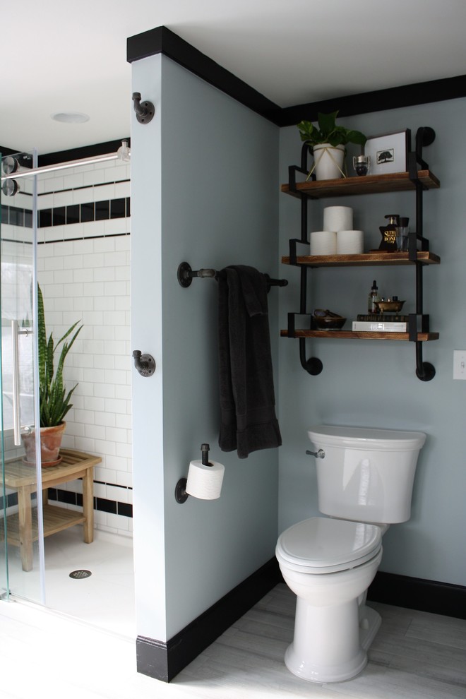 This is an example of a medium sized urban ensuite bathroom in Wichita with an alcove shower, a two-piece toilet, white tiles, metro tiles, blue walls, laminate floors, a console sink, marble worktops, white floors, a sliding door and white worktops.