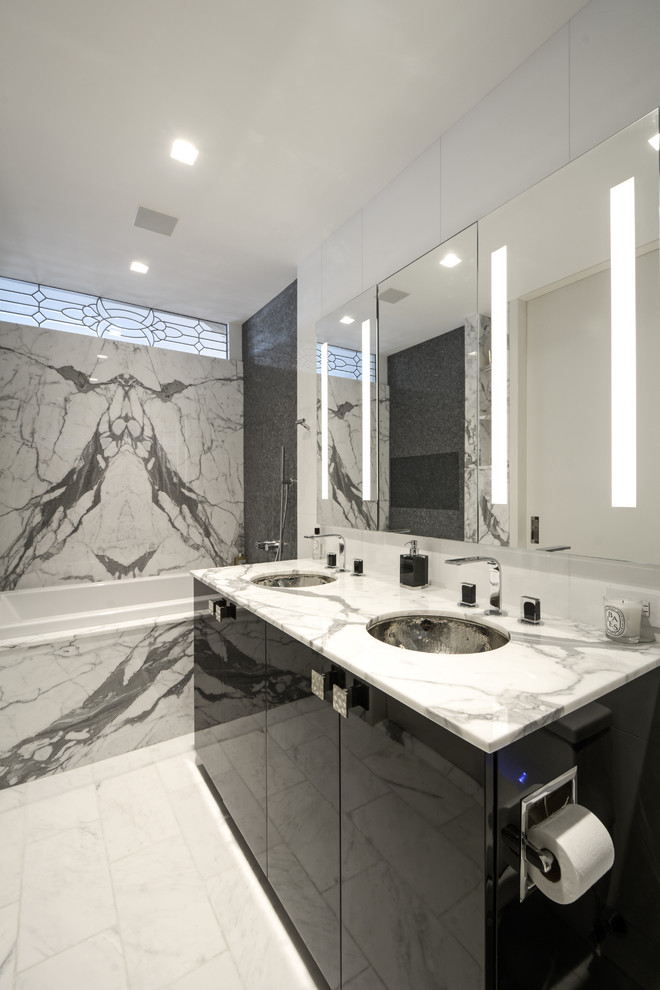 ニューヨークにあるトランジショナルスタイルのおしゃれなマスターバスルーム (フラットパネル扉のキャビネット、黒いキャビネット、ドロップイン型浴槽、シャワー付き浴槽	、アンダーカウンター洗面器、大理石の洗面台、白い床、オープンシャワー) の写真