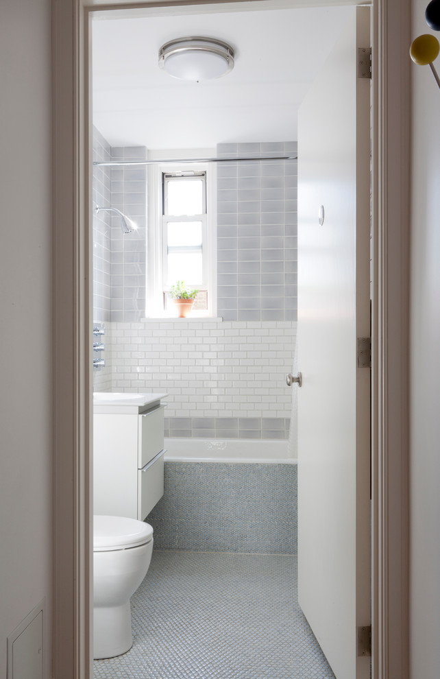Alcove bathtub - small modern blue tile and ceramic tile mosaic tile floor alcove bathtub idea in New York with an integrated sink, flat-panel cabinets, white cabinets, solid surface countertops, a one-piece toilet and blue walls