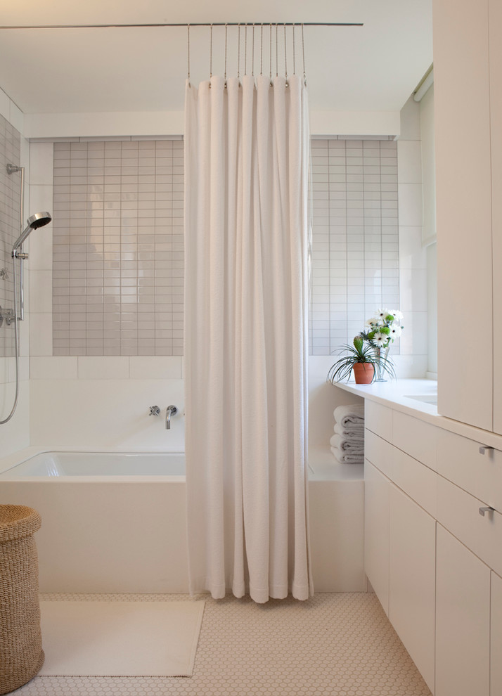 ニューヨークにあるコンテンポラリースタイルのおしゃれな浴室 (アンダーカウンター洗面器、フラットパネル扉のキャビネット、白いキャビネット、アンダーマウント型浴槽、シャワー付き浴槽	、グレーのタイル) の写真