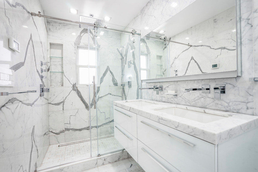 Idéer för att renovera ett stort funkis vit vitt en-suite badrum, med luckor med glaspanel, vita skåp, ett platsbyggt badkar, en öppen dusch, en vägghängd toalettstol, svart och vit kakel, stenhäll, vita väggar, marmorgolv, ett nedsänkt handfat, marmorbänkskiva, vitt golv och dusch med gångjärnsdörr