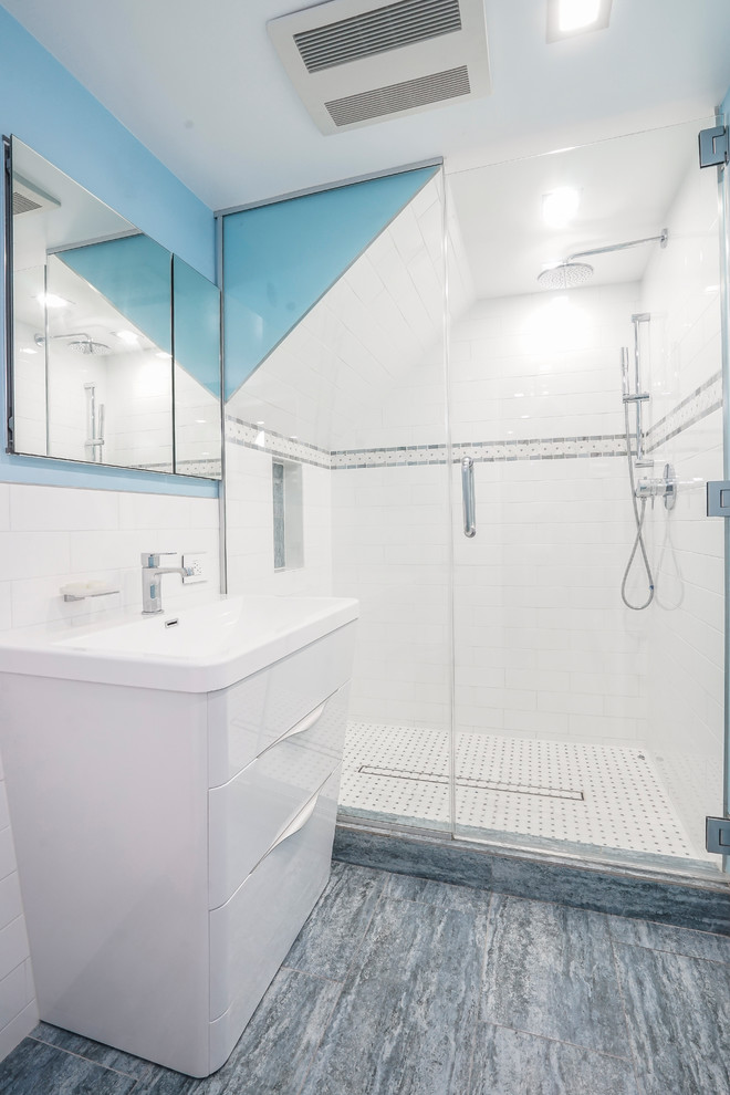 Inredning av ett modernt stort vit vitt badrum för barn, med släta luckor, vita skåp, en dusch i en alkov, en vägghängd toalettstol, vit kakel, tunnelbanekakel, blå väggar, marmorgolv, ett nedsänkt handfat, bänkskiva i onyx, blått golv och dusch med gångjärnsdörr