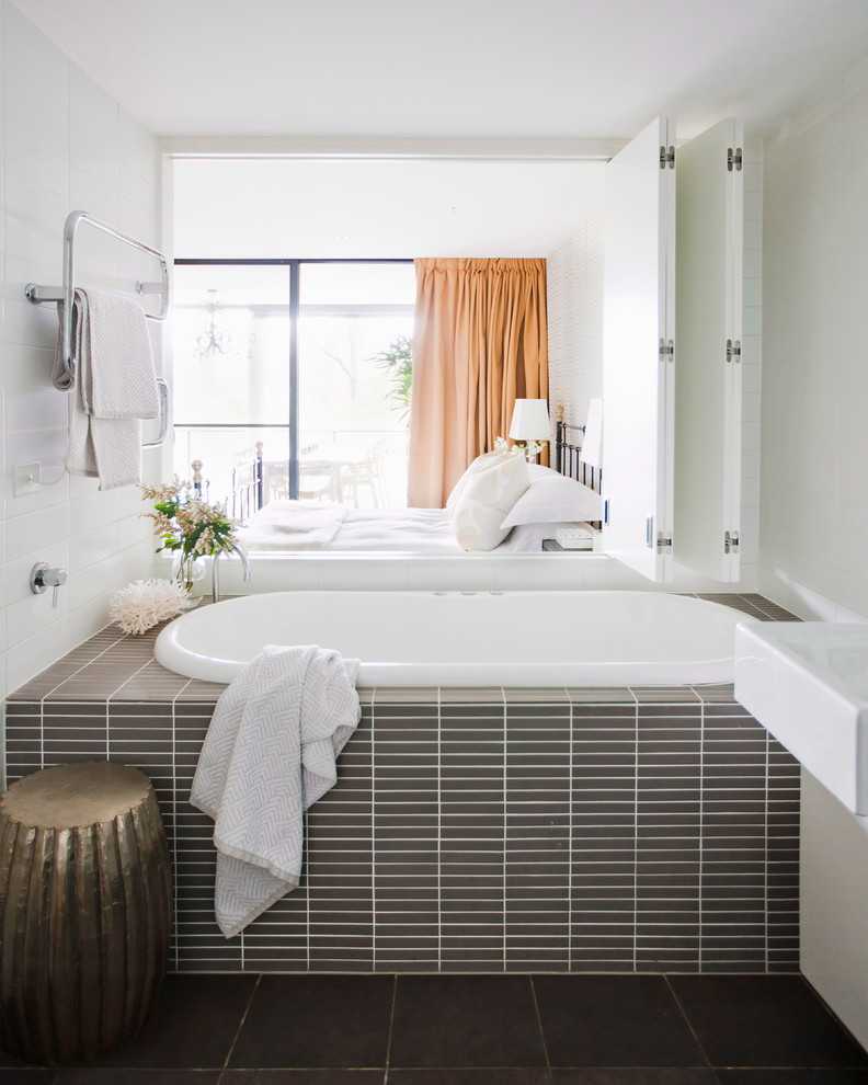 Cette image montre une salle de bain grise et blanche design avec une baignoire posée et un mur blanc.