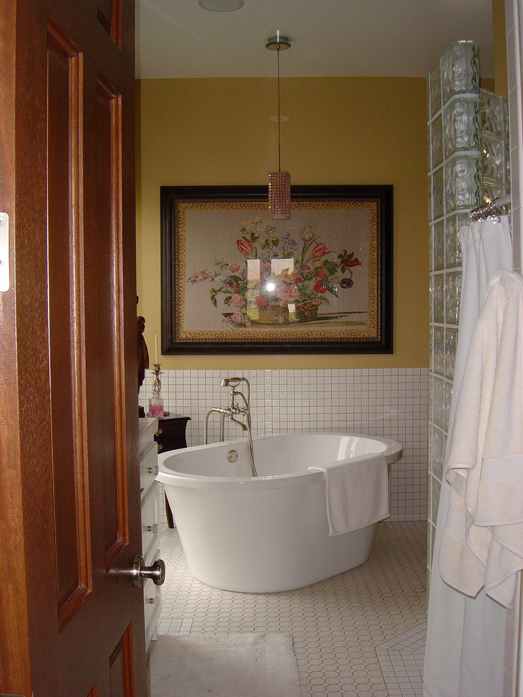 Свежая идея для дизайна: главная ванная комната среднего размера в классическом стиле с фасадами с утопленной филенкой, белыми фасадами, отдельно стоящей ванной, унитазом-моноблоком, белой плиткой, желтыми стенами и полом из мозаичной плитки - отличное фото интерьера