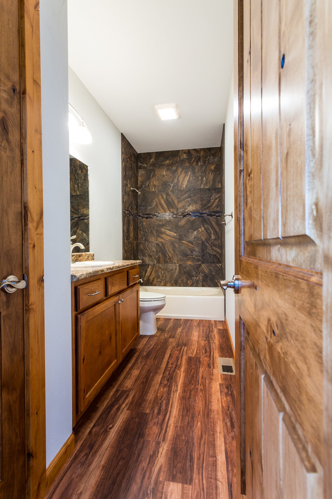 Ispirazione per una stanza da bagno tradizionale di medie dimensioni con lavabo da incasso, ante lisce, ante in legno bruno, top in granito, vasca ad alcova, pareti bianche e parquet scuro