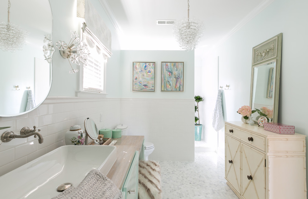 Diseño de cuarto de baño romántico con puertas de armario turquesas, paredes blancas, suelo con mosaicos de baldosas, lavabo sobreencimera, encimera de madera y suelo blanco