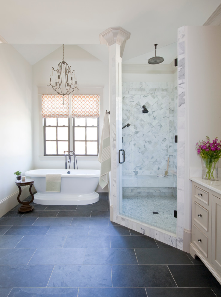 Inredning av ett klassiskt badrum, med luckor med infälld panel, beige skåp, marmorbänkskiva, ett fristående badkar, en hörndusch, vit kakel, stenkakel, vita väggar, skiffergolv och grått golv