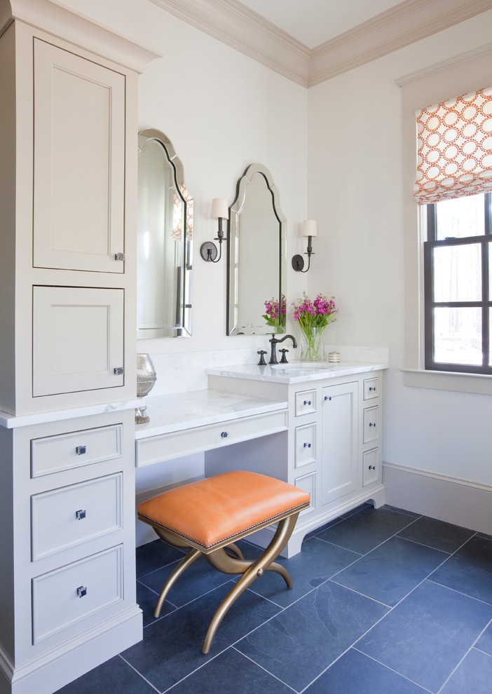 Modelo de cuarto de baño clásico con lavabo bajoencimera, armarios con paneles empotrados, puertas de armario beige, encimera de mármol, paredes blancas y suelo negro