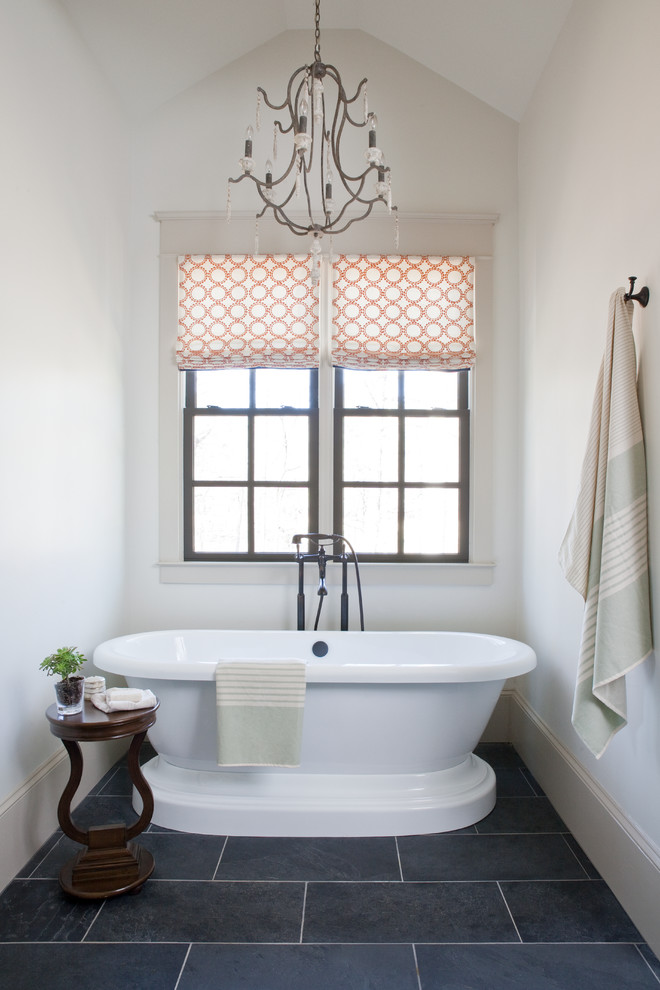 На фото: ванная комната в классическом стиле с отдельно стоящей ванной, белыми стенами и полом из сланца с