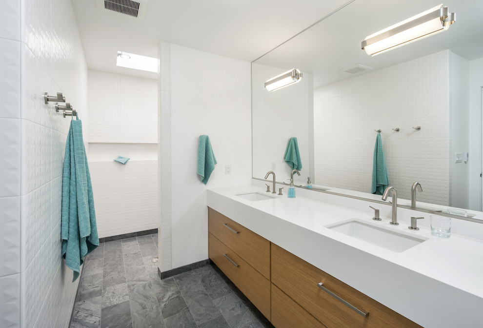 Inredning av ett modernt mellanstort vit vitt en-suite badrum, med släta luckor, skåp i mellenmörkt trä, bänkskiva i kvarts, vit kakel, ett undermonterad handfat, vita väggar, med dusch som är öppen, en kantlös dusch, en toalettstol med hel cisternkåpa, keramikplattor, skiffergolv och grått golv