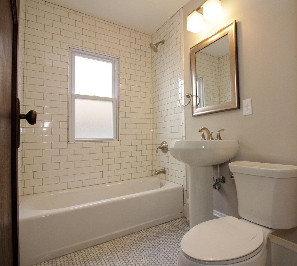 Kleines Klassisches Duschbad mit Einbaubadewanne, Wandtoilette mit Spülkasten, weißen Fliesen, Keramikfliesen, beiger Wandfarbe, Marmorboden und Sockelwaschbecken in Milwaukee