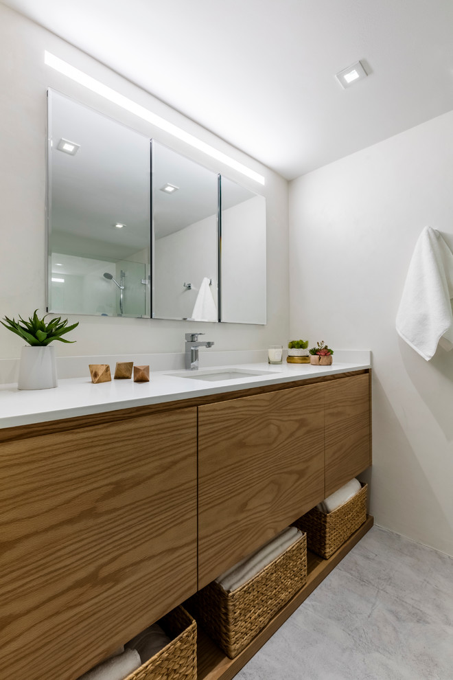Modernes Badezimmer mit flächenbündigen Schrankfronten, hellbraunen Holzschränken, weißer Wandfarbe und Unterbauwaschbecken in Miami