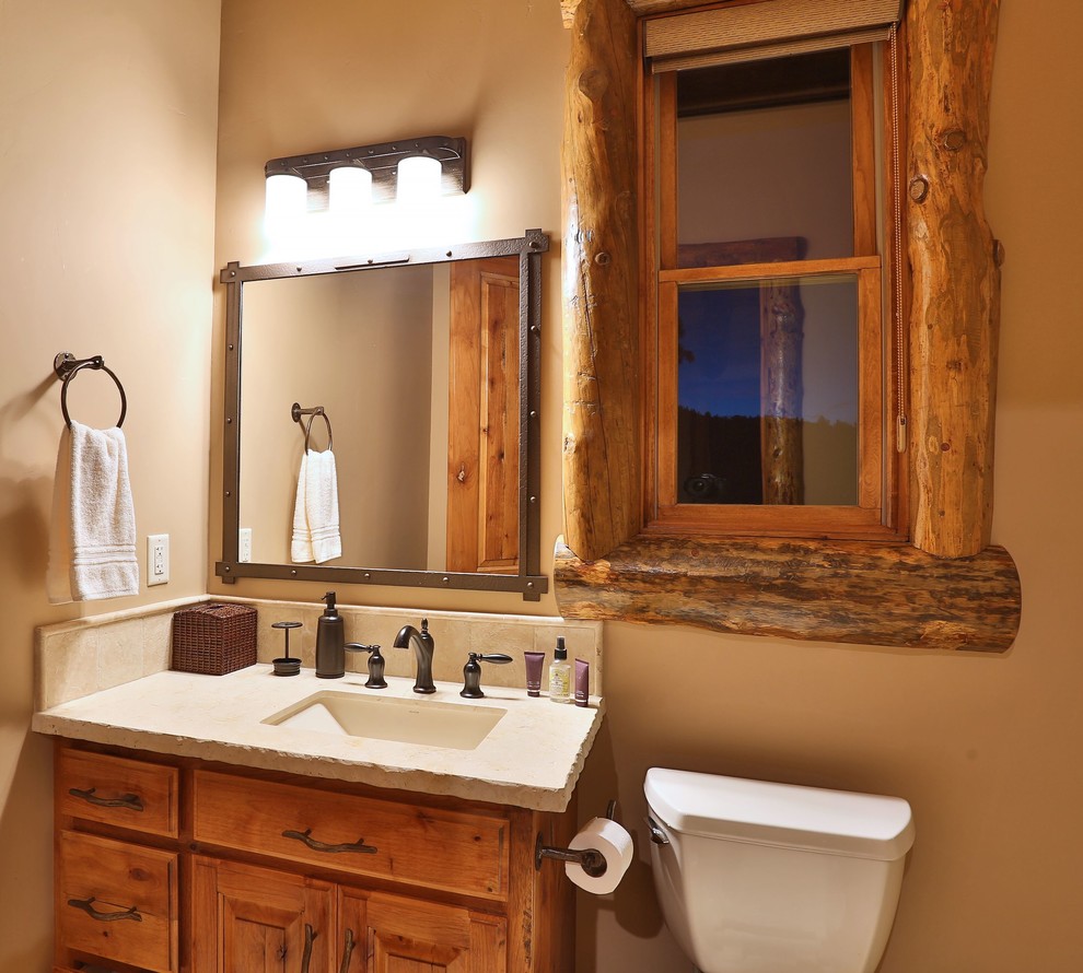 Rustik inredning av ett mellanstort badrum med dusch, med ett undermonterad handfat, luckor med upphöjd panel, skåp i mellenmörkt trä, bänkskiva i betong, en toalettstol med hel cisternkåpa och beige väggar