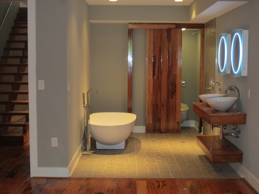 Bathroom - mid-sized contemporary ceramic tile medium tone wood floor bathroom idea in Houston with a wall-mount sink, wood countertops, a one-piece toilet and gray walls