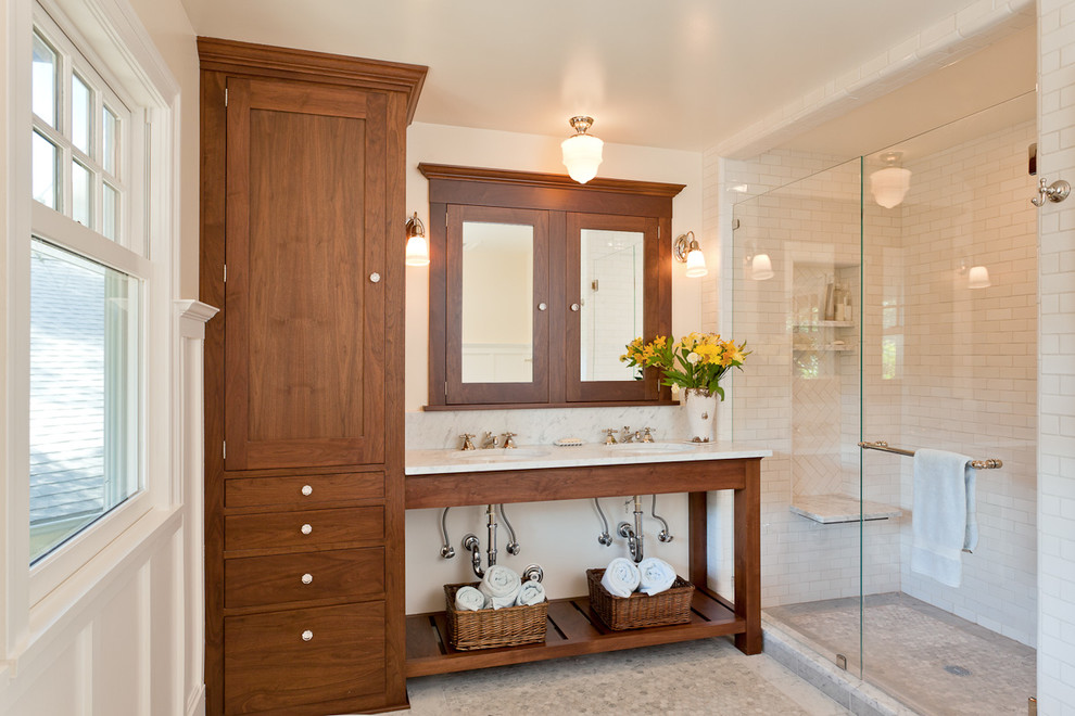 Inredning av ett modernt mellanstort vit vitt badrum med dusch, med ett undermonterad handfat, öppna hyllor, skåp i mellenmörkt trä, en dusch i en alkov, vit kakel, tunnelbanekakel, vita väggar, klinkergolv i småsten, vitt golv, ett badkar med tassar, en toalettstol med separat cisternkåpa, marmorbänkskiva och dusch med gångjärnsdörr
