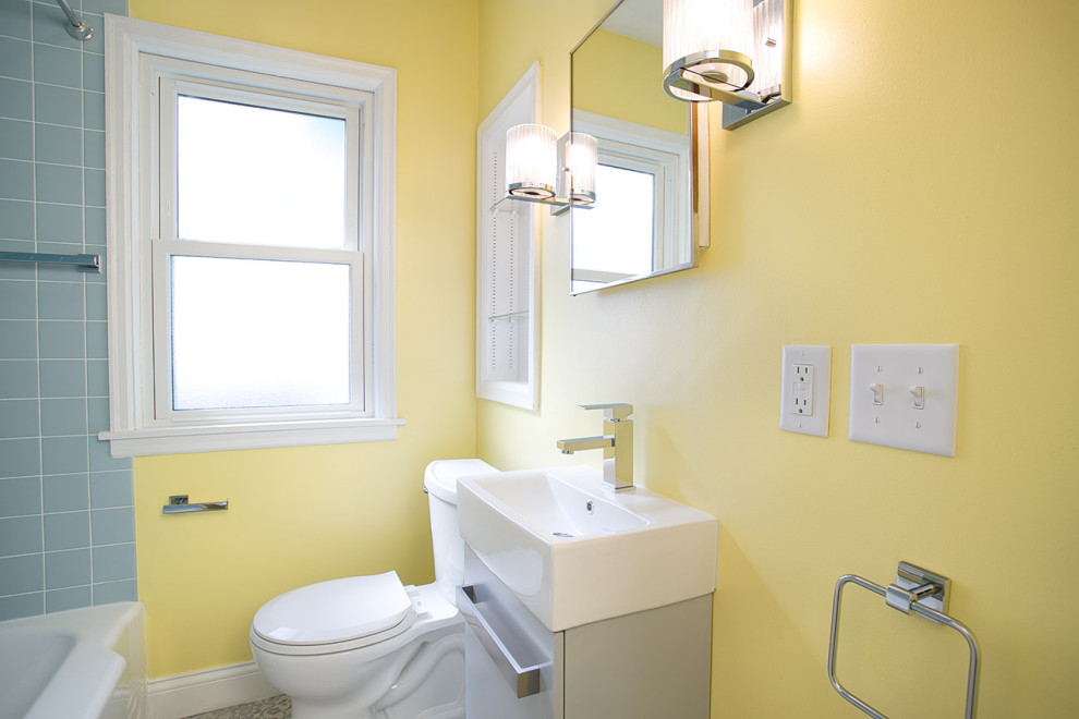 Réalisation d'une petite salle de bain principale vintage avec un placard à porte plane, des portes de placard grises, une baignoire posée, un combiné douche/baignoire, WC à poser, un carrelage bleu, des carreaux de céramique, un mur jaune, un sol en vinyl, un plan de toilette en surface solide, un sol gris, une cabine de douche avec un rideau, un plan de toilette blanc, meuble simple vasque et meuble-lavabo encastré.