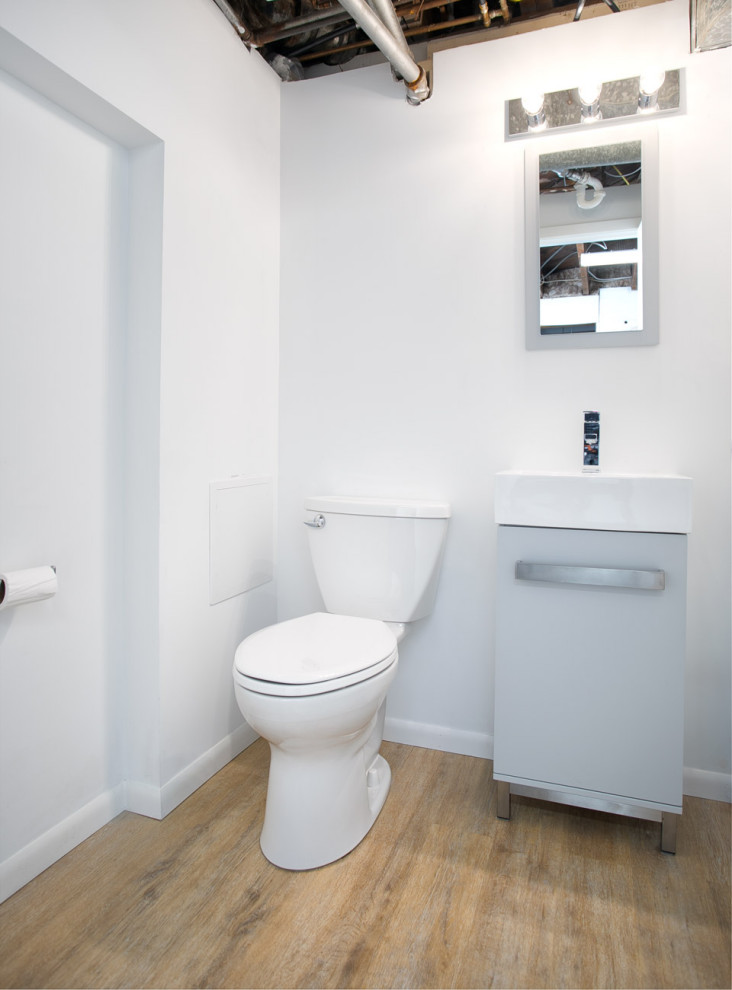 Réalisation d'un petit WC et toilettes vintage avec un placard à porte plane, des portes de placard grises, WC à poser, un carrelage bleu, un mur blanc, parquet clair, un plan de toilette en surface solide, un sol marron, un plan de toilette blanc et meuble-lavabo sur pied.