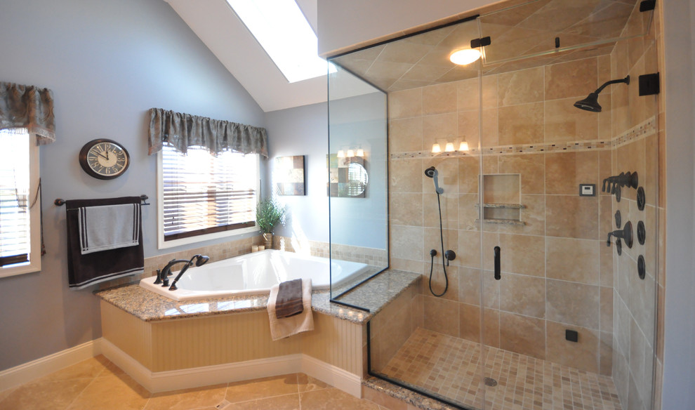 Пример оригинального дизайна: огромная главная ванная комната в стиле неоклассика (современная классика) с врезной раковиной, фасадами с выступающей филенкой, темными деревянными фасадами, столешницей из гранита, угловой ванной, двойным душем, раздельным унитазом, бежевой плиткой, керамогранитной плиткой, синими стенами и полом из травертина