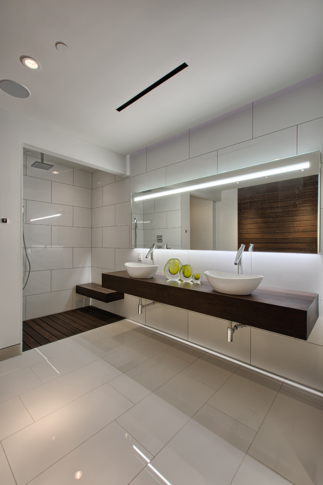 Идея дизайна: большая главная ванная комната в стиле модернизм с отдельно стоящей ванной, душем в нише, белой плиткой, белыми стенами, настольной раковиной, столешницей из дерева, белым полом, открытым душем и коричневой столешницей