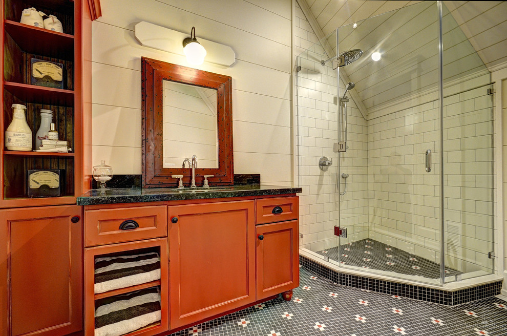 Cette image montre une salle d'eau chalet avec un lavabo encastré, un placard avec porte à panneau encastré, des portes de placard oranges, une douche d'angle, un carrelage multicolore et un mur beige.