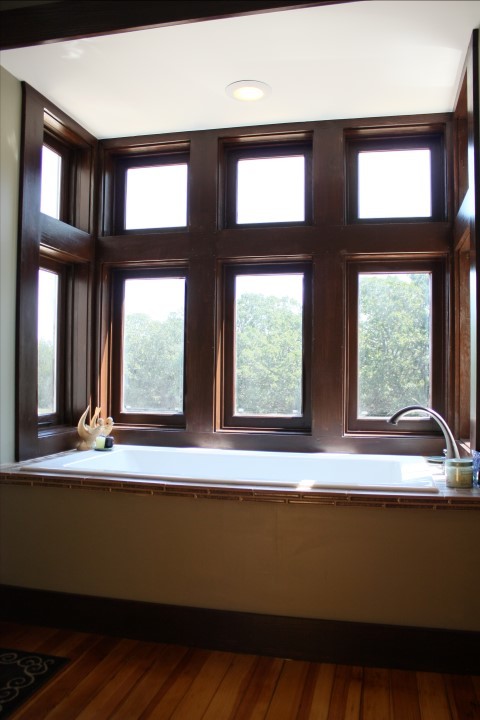 Foto på ett lantligt badrum, med kaklad bänkskiva, ett platsbyggt badkar, porslinskakel och mellanmörkt trägolv