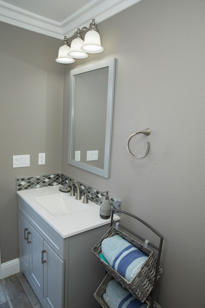 Foto de cuarto de baño contemporáneo pequeño con armarios tipo mueble, puertas de armario grises, paredes grises, suelo laminado, aseo y ducha, lavabo integrado, encimera de acrílico, suelo gris y encimeras blancas