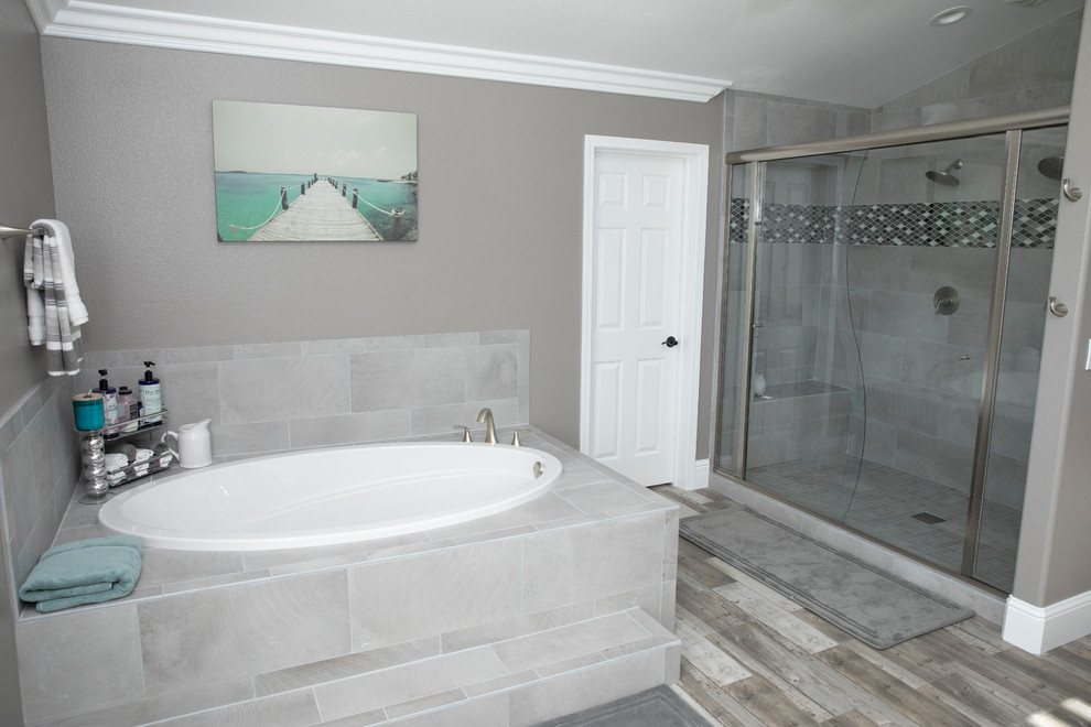 Exempel på ett litet modernt en-suite badrum, med grått golv, ett platsbyggt badkar, en dusch i en alkov, grå kakel, porslinskakel, grå väggar, laminatgolv och dusch med skjutdörr
