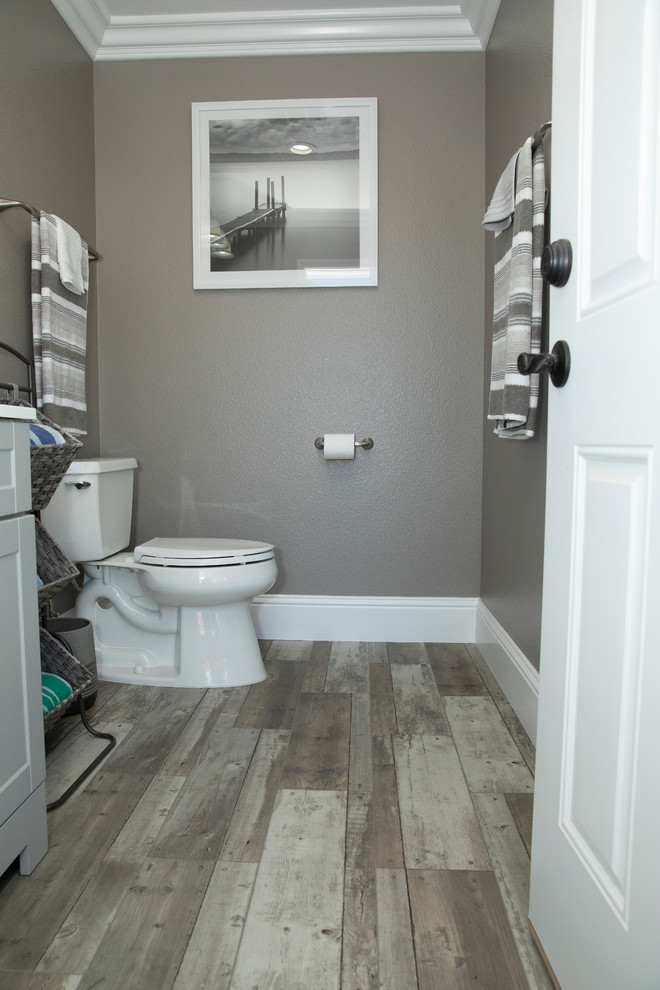 Inredning av ett modernt litet vit vitt badrum med dusch, med möbel-liknande, grå skåp, grå väggar, laminatgolv, bänkskiva i akrylsten, grått golv och en toalettstol med separat cisternkåpa