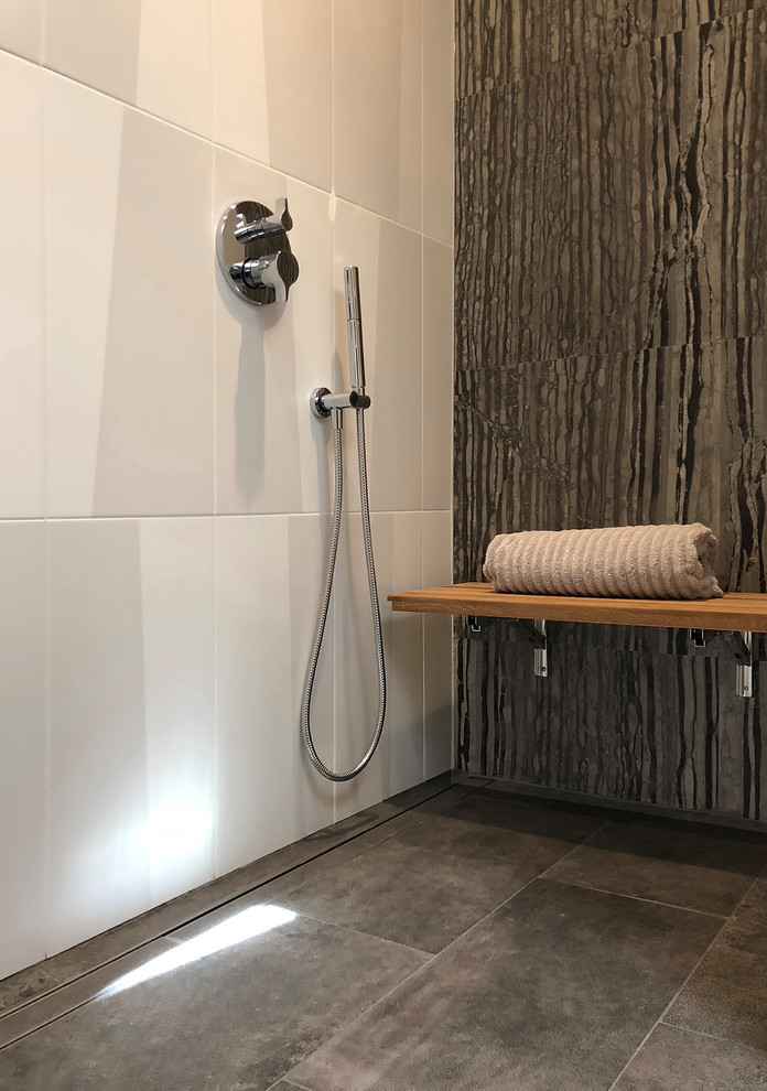 Design ideas for a medium sized modern shower room bathroom in Seattle with glass-front cabinets, grey cabinets, a built-in shower, a wall mounted toilet, black and white tiles, stone tiles, white walls, porcelain flooring, an integrated sink, glass worktops, grey floors, a hinged door and grey worktops.