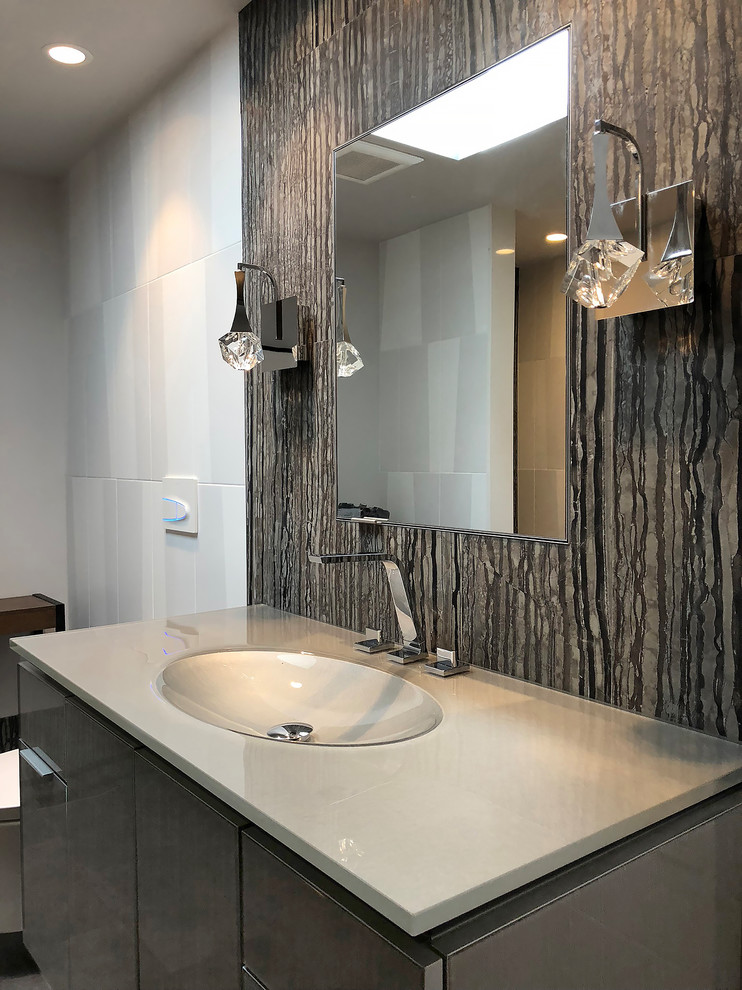Inspiration för mellanstora moderna grått badrum med dusch, med luckor med glaspanel, grå skåp, en kantlös dusch, en vägghängd toalettstol, svart och vit kakel, stenkakel, vita väggar, klinkergolv i porslin, ett integrerad handfat, bänkskiva i glas, grått golv och dusch med gångjärnsdörr