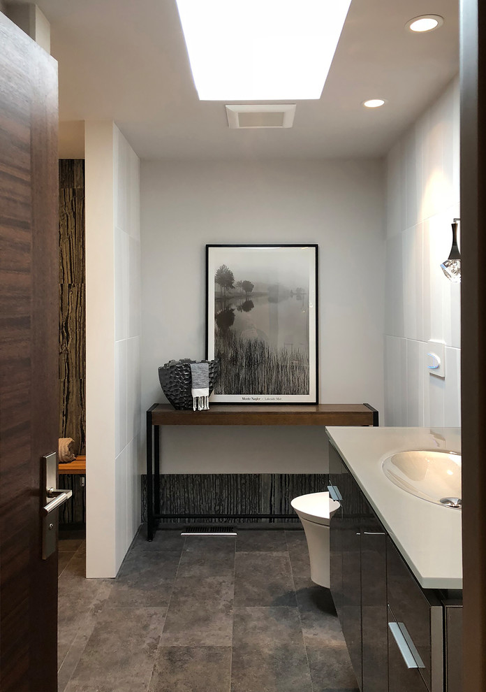 Inspiration for a medium sized modern shower room bathroom in Seattle with glass-front cabinets, grey cabinets, a built-in shower, a wall mounted toilet, black and white tiles, stone tiles, white walls, porcelain flooring, an integrated sink, glass worktops, grey floors, a hinged door and grey worktops.