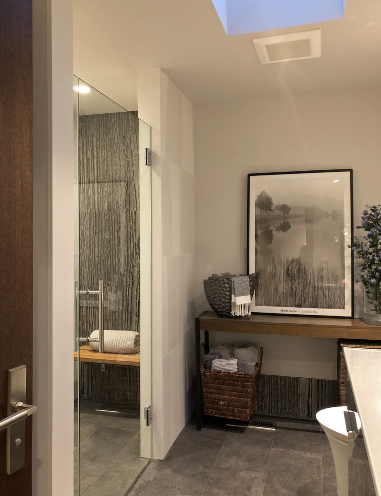 Пример оригинального дизайна: ванная комната среднего размера в стиле модернизм с стеклянными фасадами, серыми фасадами, душем без бортиков, инсталляцией, черно-белой плиткой, каменной плиткой, белыми стенами, полом из керамогранита, душевой кабиной, монолитной раковиной, стеклянной столешницей, серым полом, душем с распашными дверями и серой столешницей