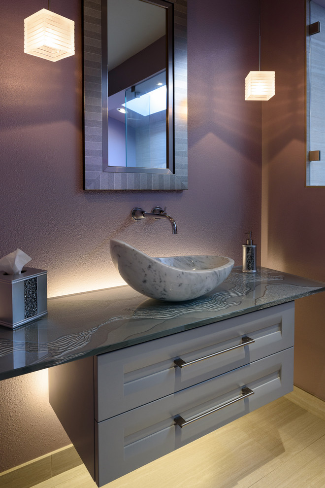 Bild på ett mellanstort funkis badrum med dusch, med luckor med infälld panel, en öppen dusch, en vägghängd toalettstol, grå kakel, porslinskakel, klinkergolv i porslin, ett fristående handfat, bänkskiva i glas, lila väggar och grå skåp