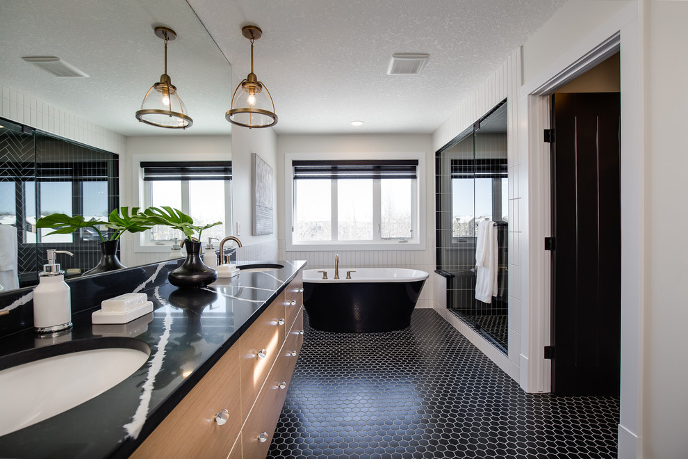 This is an example of a traditional ensuite bathroom in Calgary with flat-panel cabinets, medium wood cabinets, a freestanding bath, an alcove shower, black tiles, white walls, mosaic tile flooring, a submerged sink, black floors, a hinged door and black worktops.