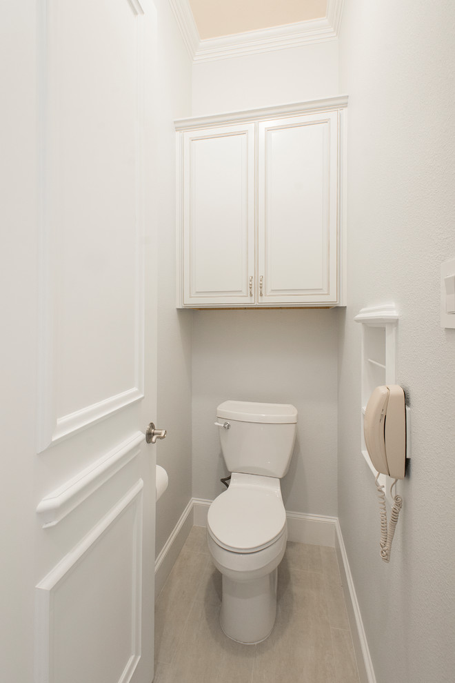 Cette photo montre un WC et toilettes chic en bois vieilli de taille moyenne avec un carrelage gris, des carreaux de céramique, un mur gris, un sol en carrelage de porcelaine, un sol gris, un placard avec porte à panneau surélevé, WC séparés, un lavabo encastré, un plan de toilette en marbre et un plan de toilette blanc.