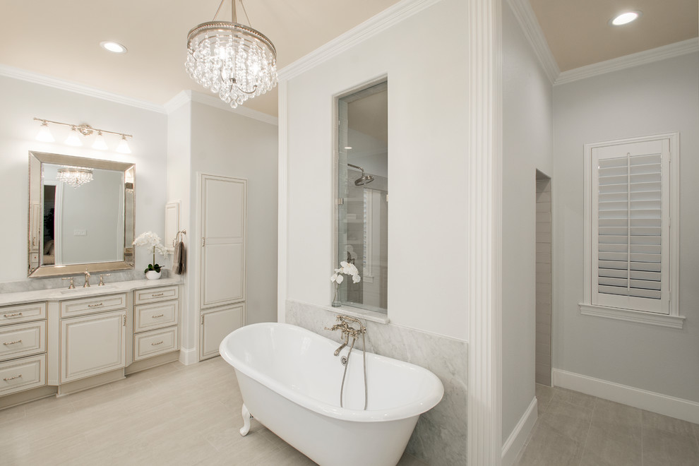 Klassisk inredning av ett mellanstort vit vitt en-suite badrum, med ett fristående badkar, en dubbeldusch, grå kakel, keramikplattor, grå väggar, klinkergolv i porslin, grått golv, med dusch som är öppen, luckor med upphöjd panel, skåp i slitet trä, en toalettstol med separat cisternkåpa, ett undermonterad handfat och marmorbänkskiva