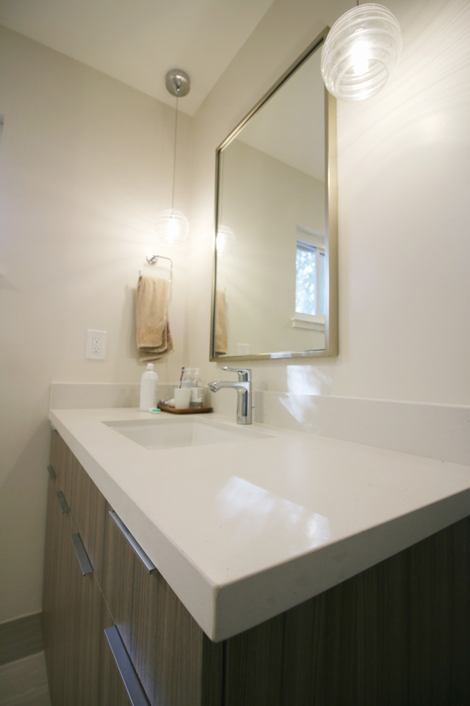 Inredning av ett modernt badrum, med en hörndusch, grå kakel, klinkergolv i porslin, ett undermonterad handfat och dusch med gångjärnsdörr