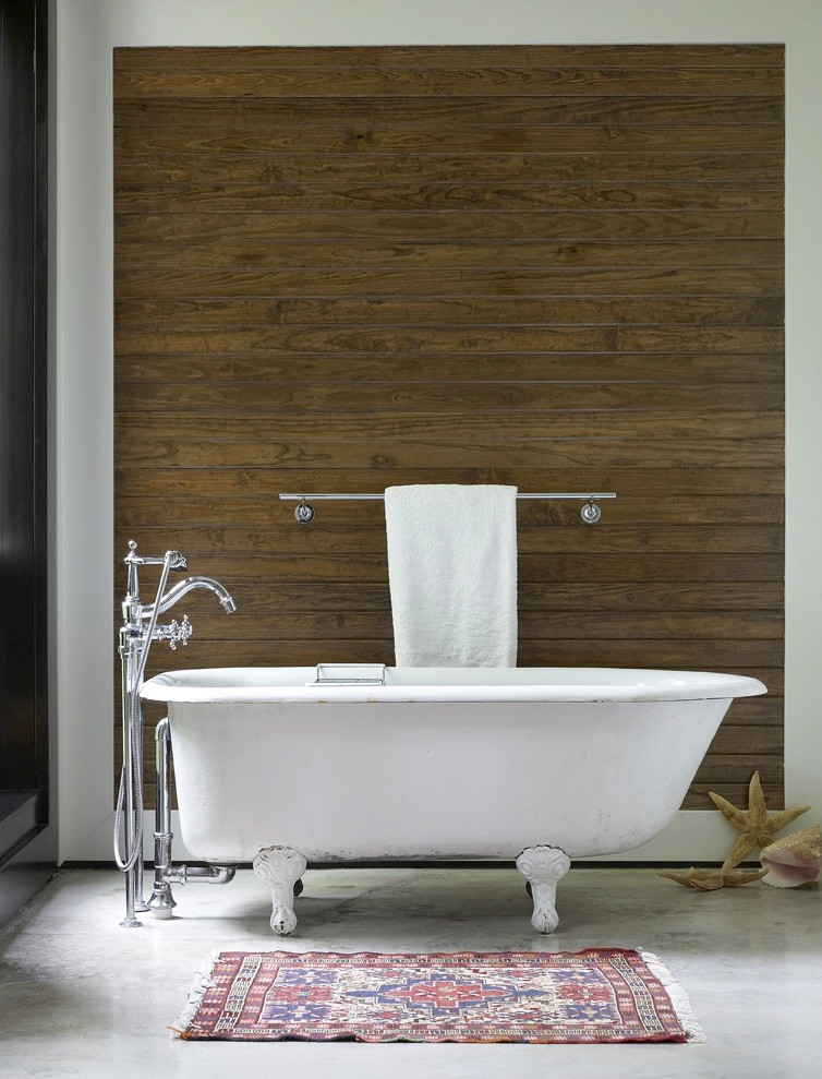 Foto de cuarto de baño principal exótico con bañera con patas y suelo de cemento