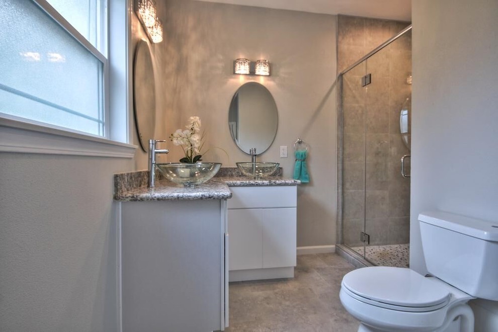 Inspiration for a mid-sized contemporary 3/4 brown tile and ceramic tile ceramic tile and beige floor alcove shower remodel in San Francisco with flat-panel cabinets, white cabinets, a two-piece toilet, beige walls, a vessel sink, granite countertops, a hinged shower door and multicolored countertops