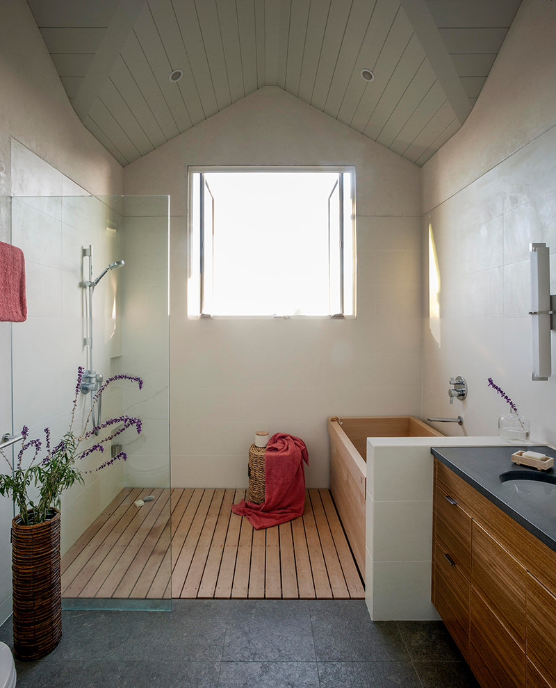 Foto på ett mellanstort lantligt en-suite badrum, med skåp i mellenmörkt trä, en öppen dusch, ett japanskt badkar, släta luckor, grå väggar, en toalettstol med separat cisternkåpa, skiffergolv, ett undermonterad handfat, bänkskiva i akrylsten och med dusch som är öppen