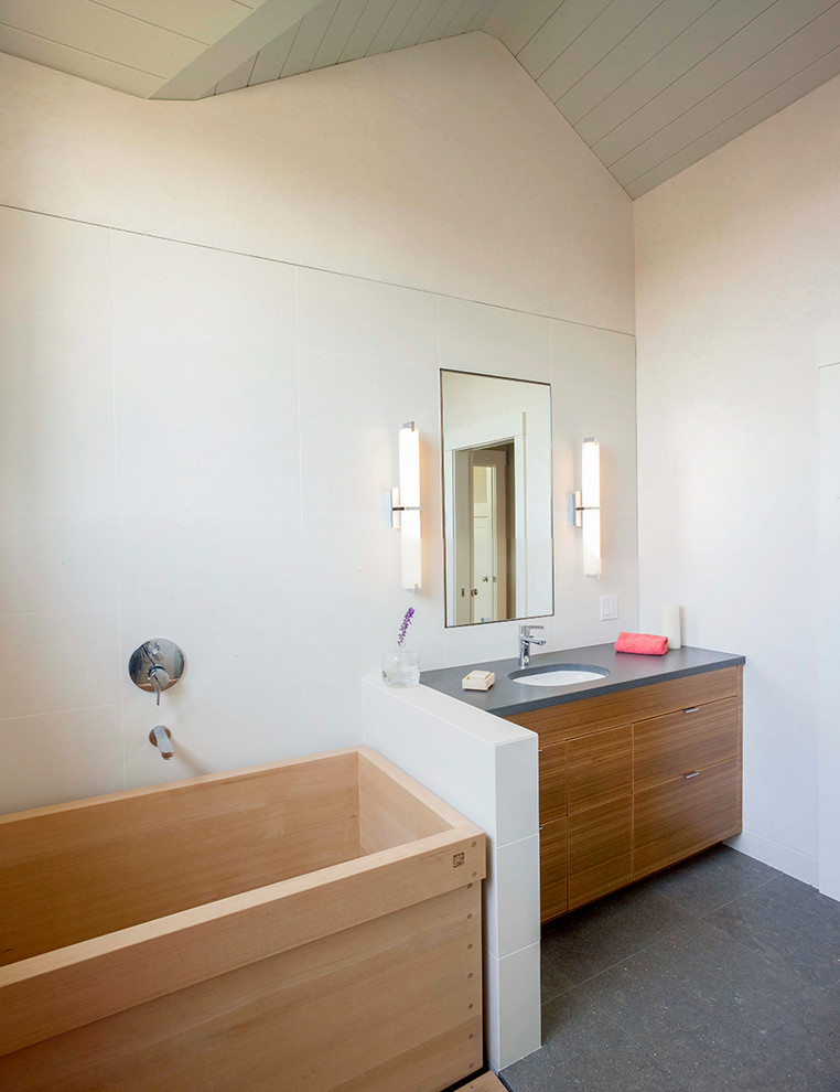 Cette image montre une salle de bain principale bohème en bois brun de taille moyenne avec un placard à porte plane, un bain japonais, une douche ouverte, un mur gris, WC séparés, un sol en ardoise, un lavabo encastré et un plan de toilette en surface solide.
