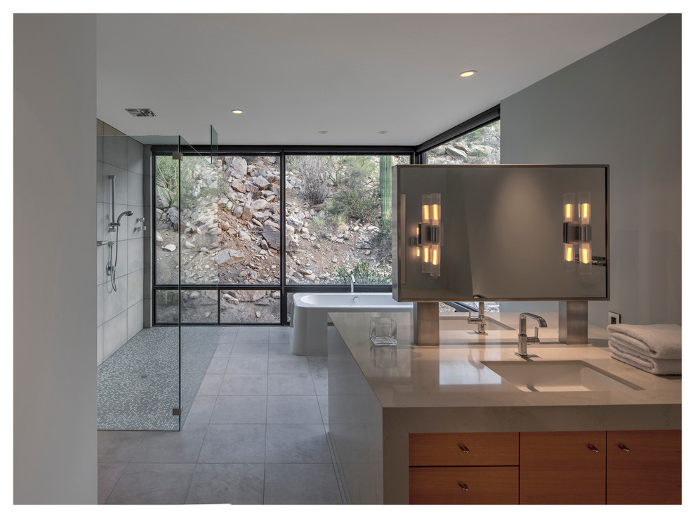 Cette photo montre une grande salle de bain principale tendance en bois brun avec un lavabo posé, un placard à porte plane, un plan de toilette en béton, une baignoire indépendante, une douche à l'italienne, un carrelage gris, des carreaux de béton et un mur gris.