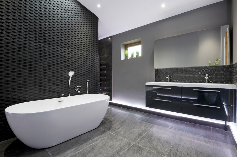 Идея дизайна: большая главная ванная комната в современном стиле с черными фасадами, отдельно стоящей ванной, черной плиткой, серыми стенами, полом из керамогранита, белой столешницей, плоскими фасадами и серым полом