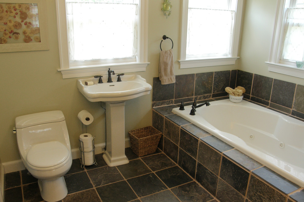 Immagine di una grande stanza da bagno padronale tradizionale con lavabo a colonna, vasca idromassaggio, doccia ad angolo, WC monopezzo, piastrelle grigie, piastrelle in pietra, pareti verdi e pavimento in ardesia
