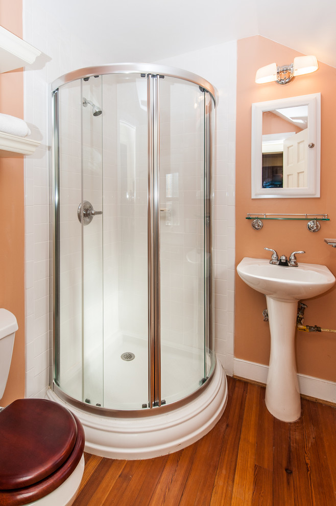 Idée de décoration pour une petite salle d'eau craftsman avec un lavabo de ferme, une douche d'angle, WC séparés, un carrelage blanc, des carreaux de céramique, un mur orange et un sol en bois brun.