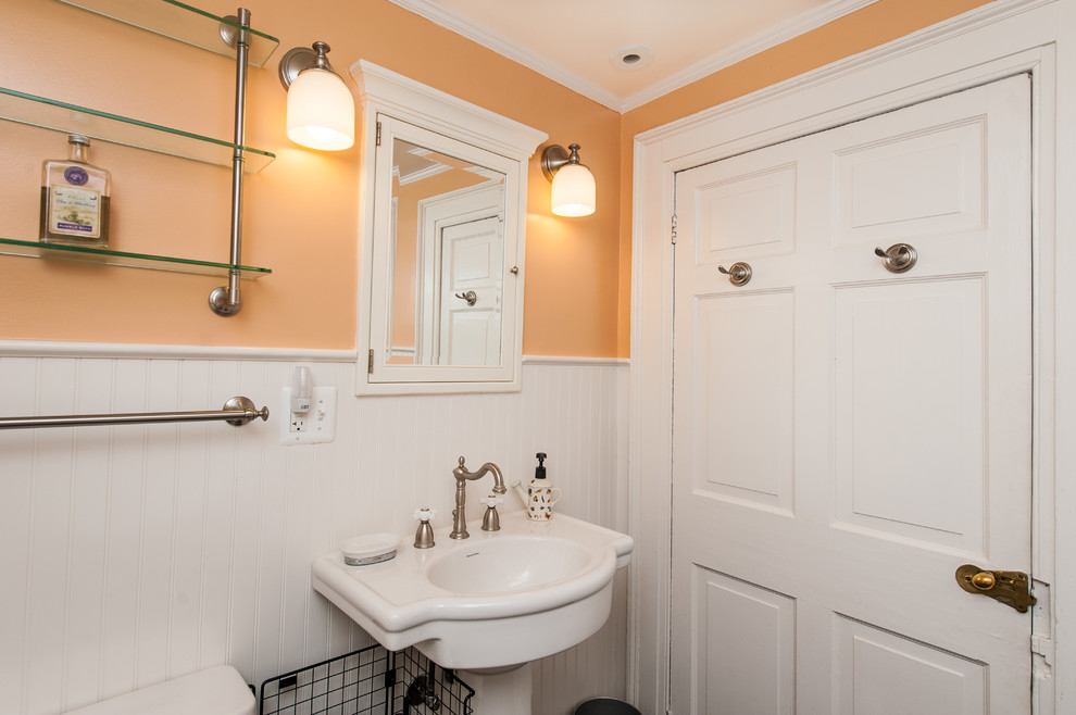 Idéer för ett litet amerikanskt badrum med dusch, med ett piedestal handfat, ett badkar med tassar, en dusch/badkar-kombination, orange väggar och mörkt trägolv