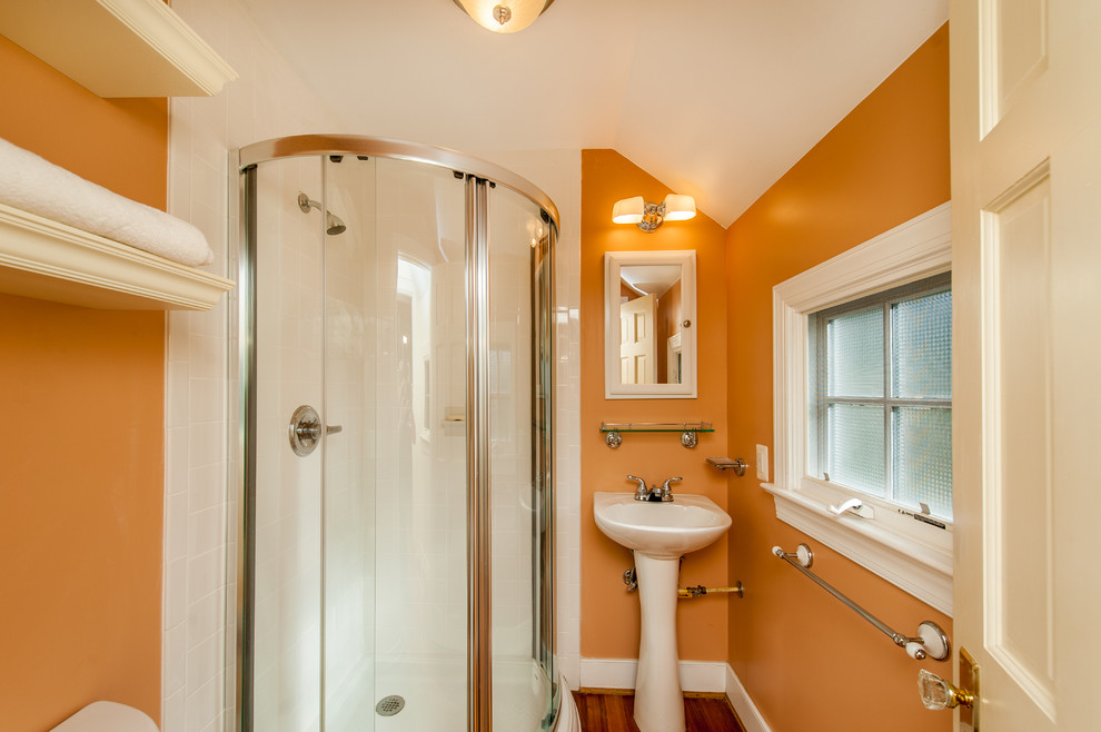 Exemple d'une petite salle d'eau craftsman avec un lavabo de ferme, une douche d'angle, WC séparés, un carrelage blanc, des carreaux de céramique, un mur orange et un sol en bois brun.