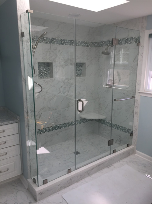 Modern inredning av ett mellanstort badrum med dusch, med luckor med upphöjd panel, vita skåp, en dusch i en alkov, en toalettstol med hel cisternkåpa, grå kakel, stenkakel, grå väggar, marmorgolv, ett undermonterad handfat, marmorbänkskiva, vitt golv och dusch med gångjärnsdörr
