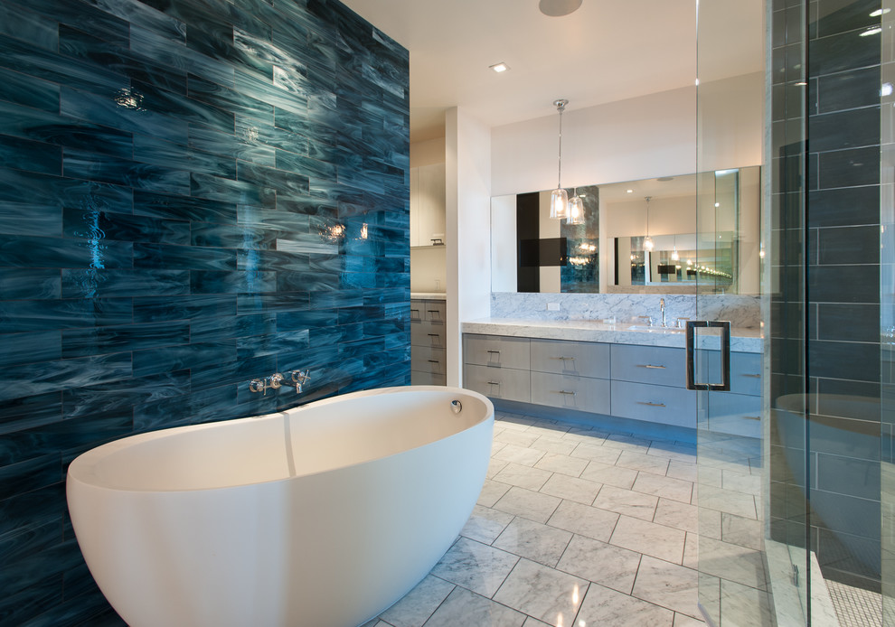 Immagine di una stanza da bagno design con ante lisce, ante grigie, vasca freestanding e piastrelle nere