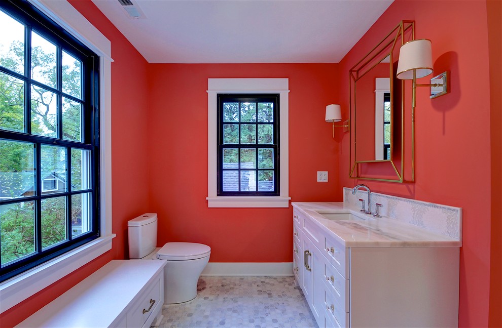 Foto på ett vintage vit badrum med dusch, med luckor med infälld panel, vita skåp, en toalettstol med separat cisternkåpa, orange väggar, ett undermonterad handfat och grått golv